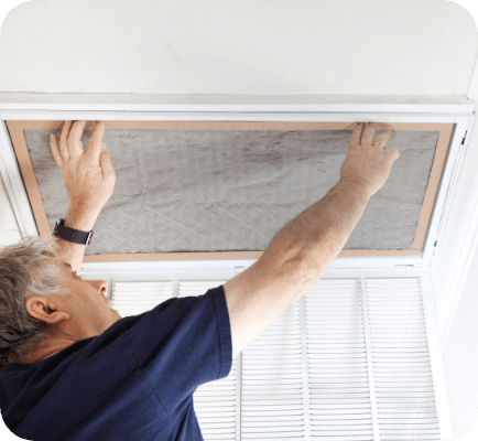 Man inserting air filter in vent in ceiling