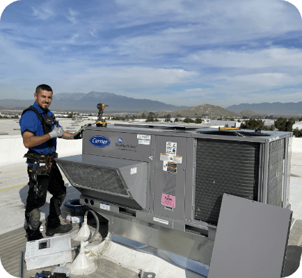 Sheldon's Heating & Air Conditioning employee next to a carrier unit on the roof